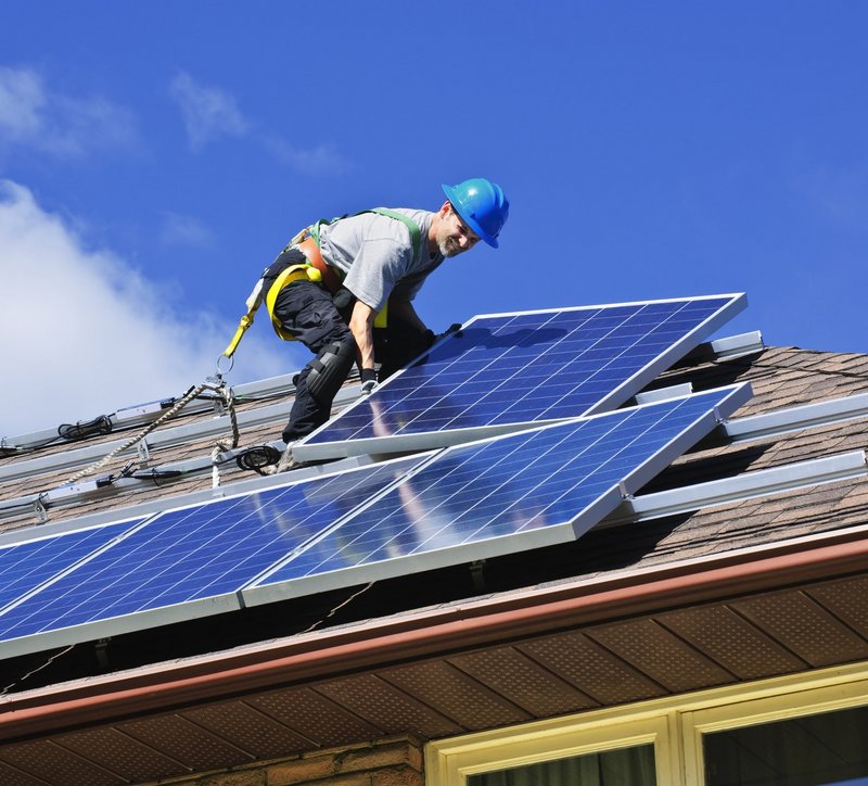 Mann installiert Photovoltaik Anlage auf einem Dach.