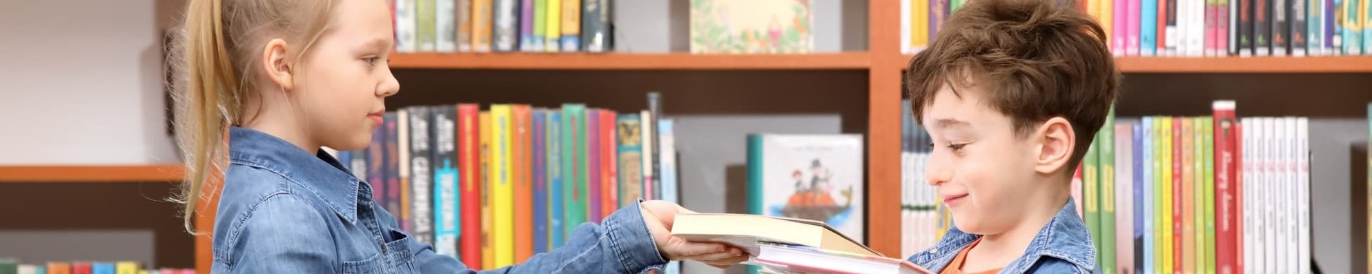 Ideen und Materialien zur Leseförderung Mädchen und Junge mit Büchern in einer Bibliothek