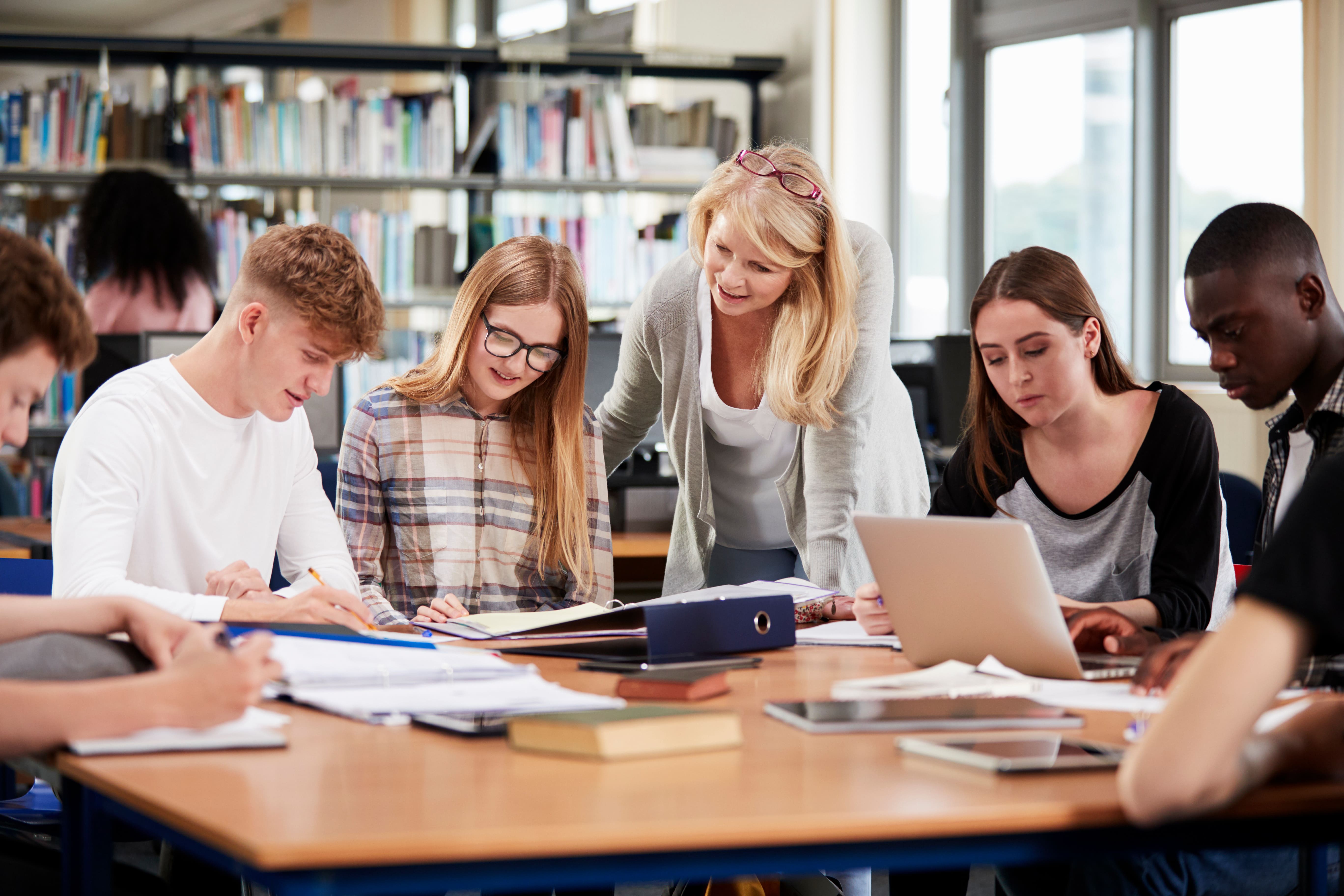 Lehrerin mit Schülerinnen und Schülerin im Gespräch