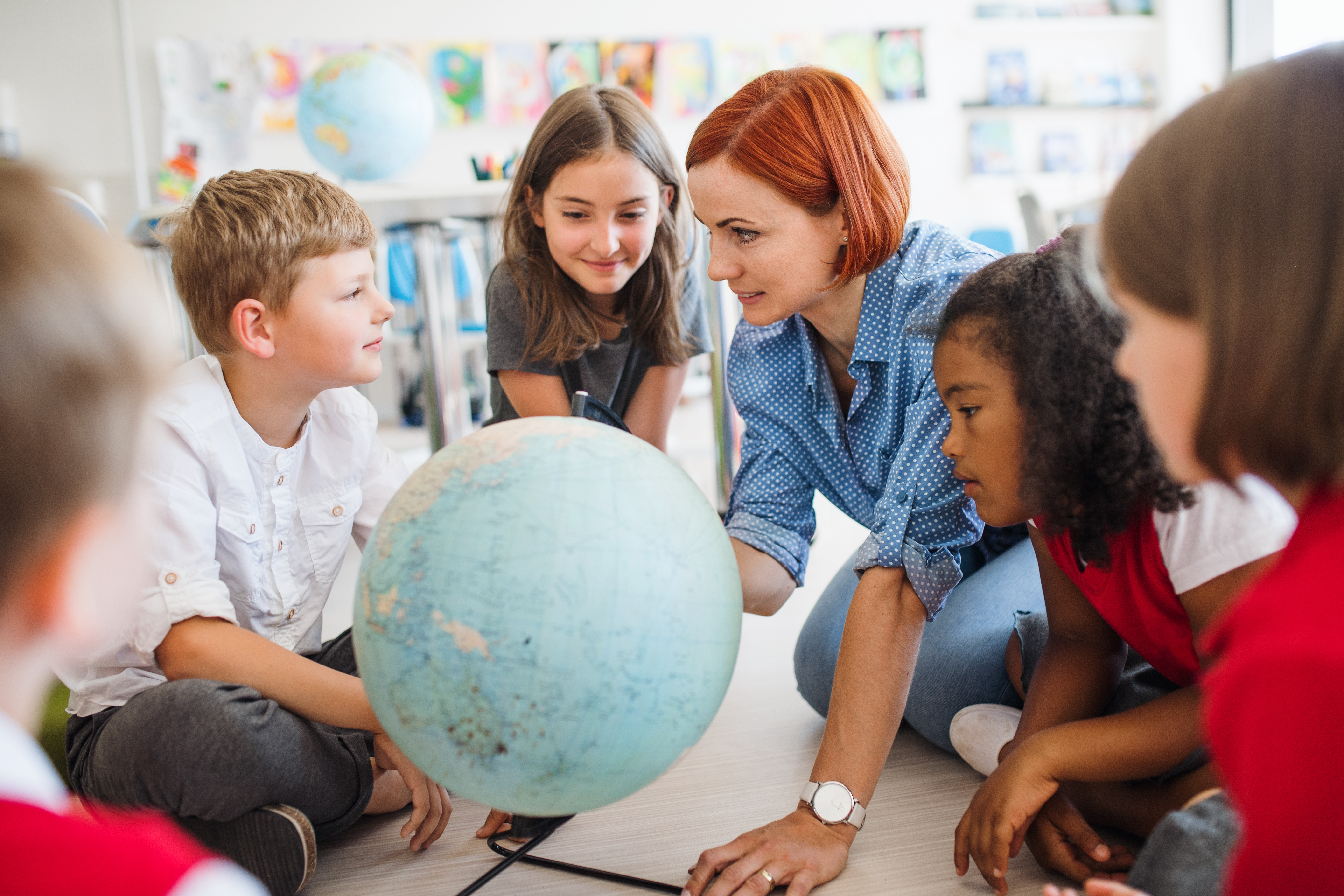 Lernende mit Lehrerin und Globus